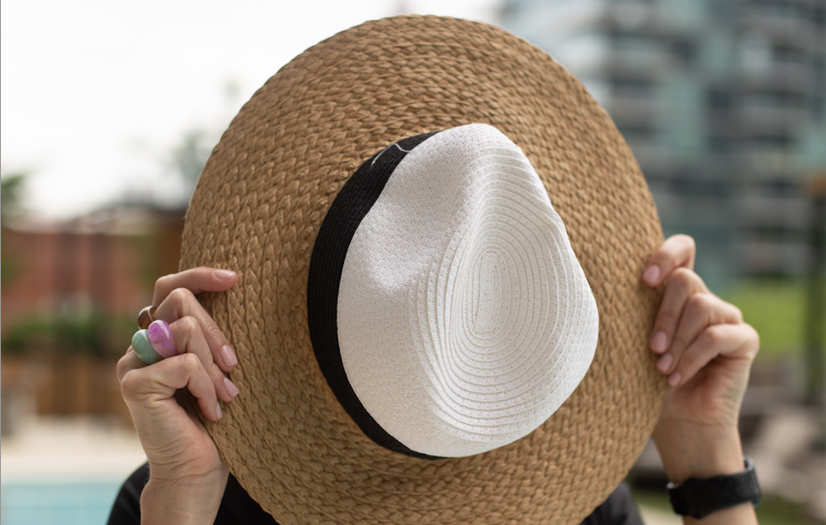 Woman shielding her face from the sun with her hat